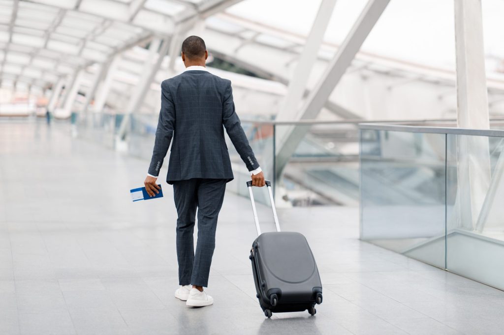 Business traveller in a suit walking through an airport terminal with a suitcase
