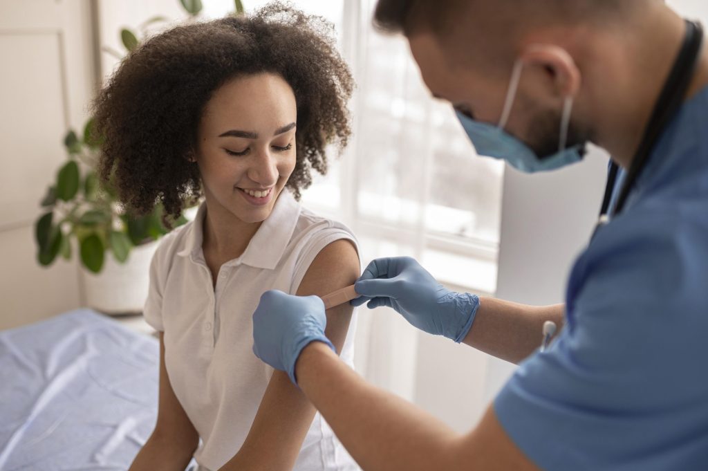 Doctor placing a plaster on a patient's arm after a travel vaccination