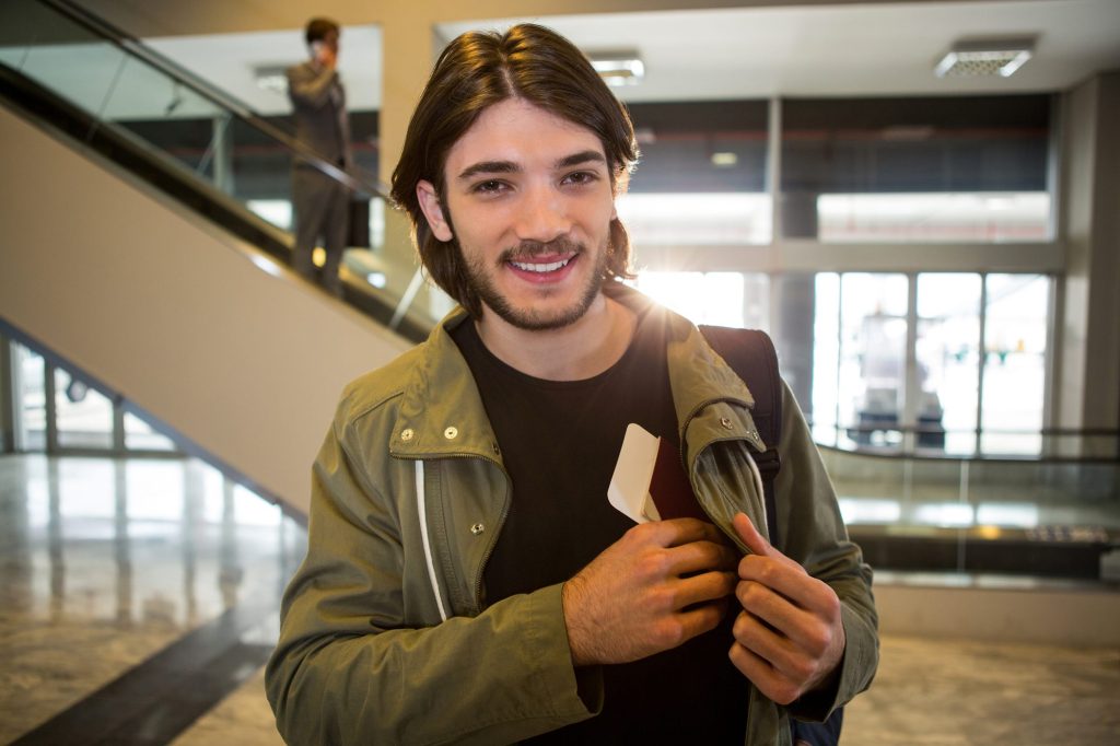 Smiling traveller placing passport into jacket pocket