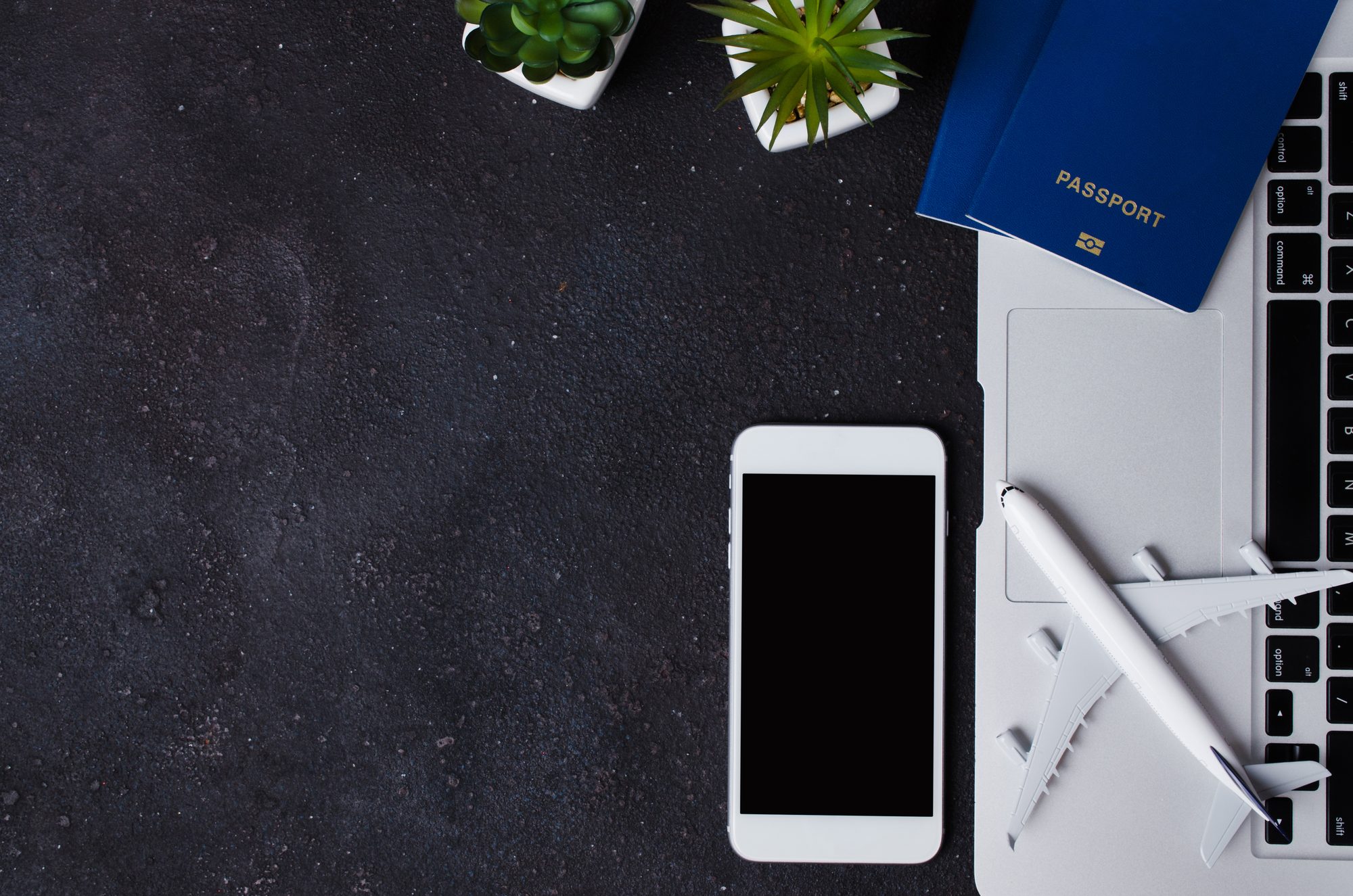 Passports, phone and laptop arranged on a dark desk ahead of a Canada visa application