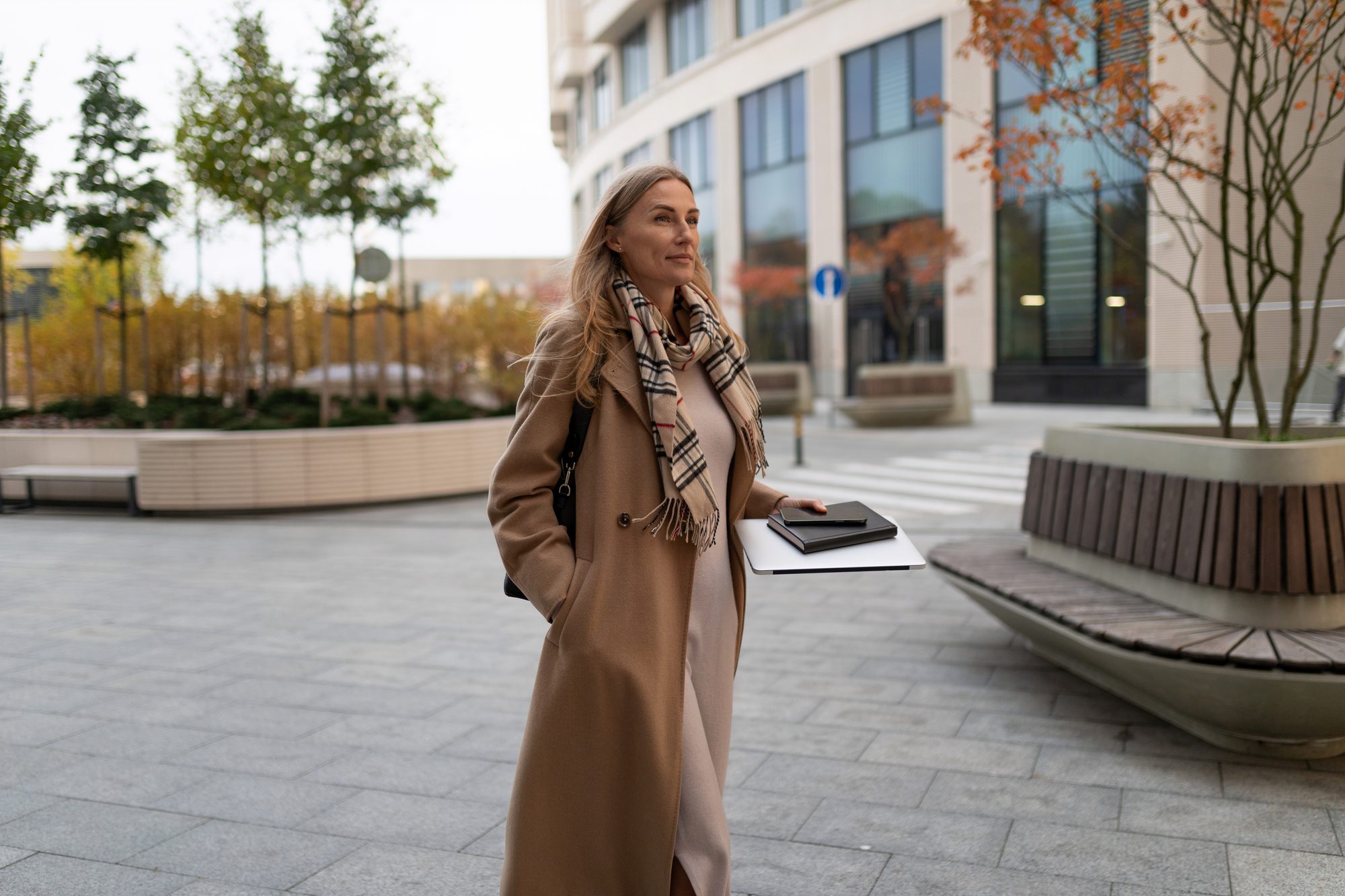 Traveller in a camel coat walking through a business precinct on an autumn day