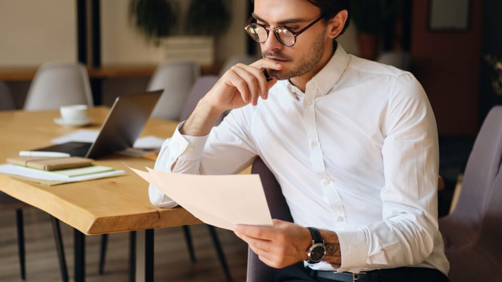 Professional calmly reviewing documents at a tidy desk by a bright window