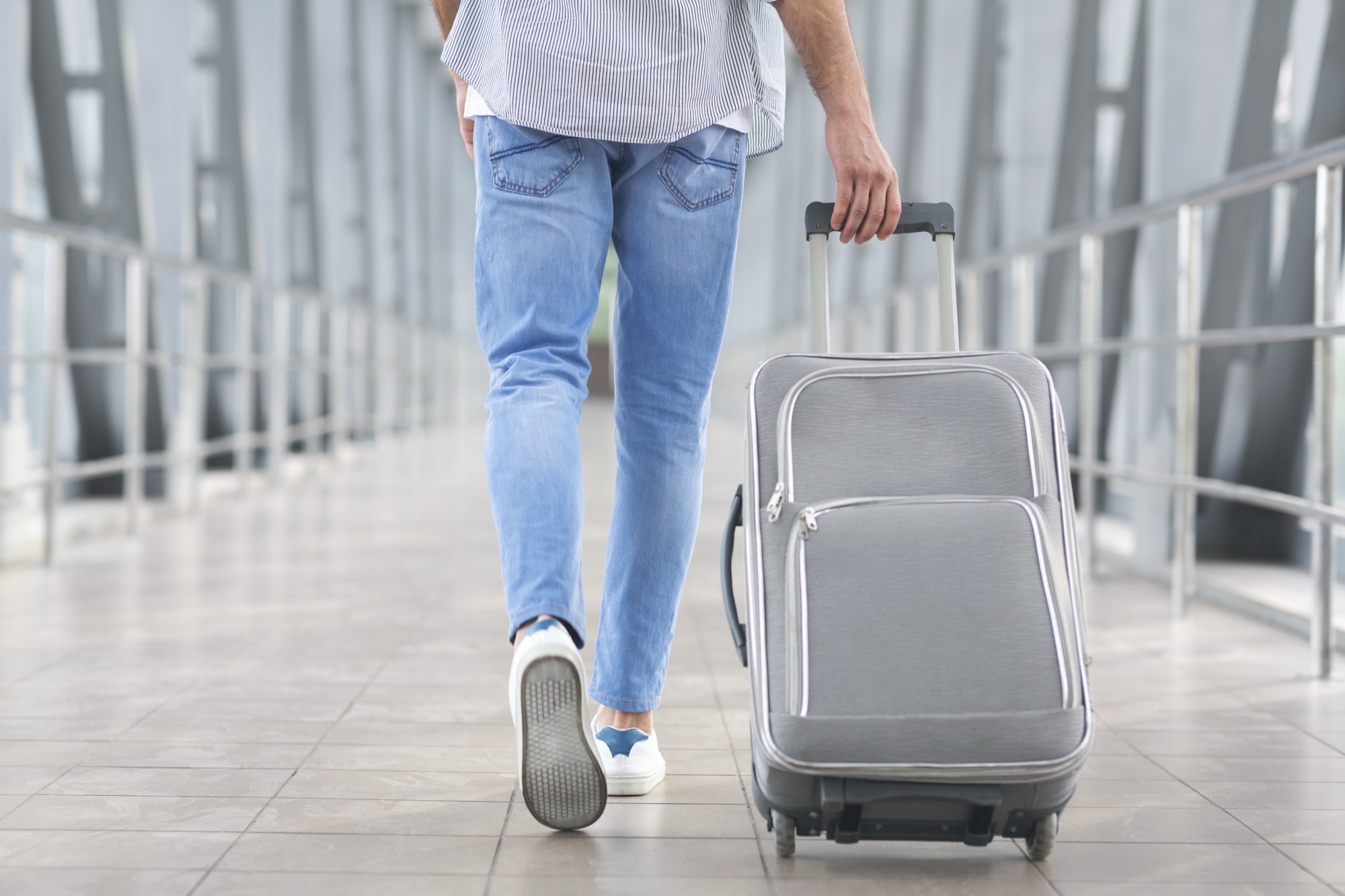 A traveller walking through an airport terminal with a wheeled case