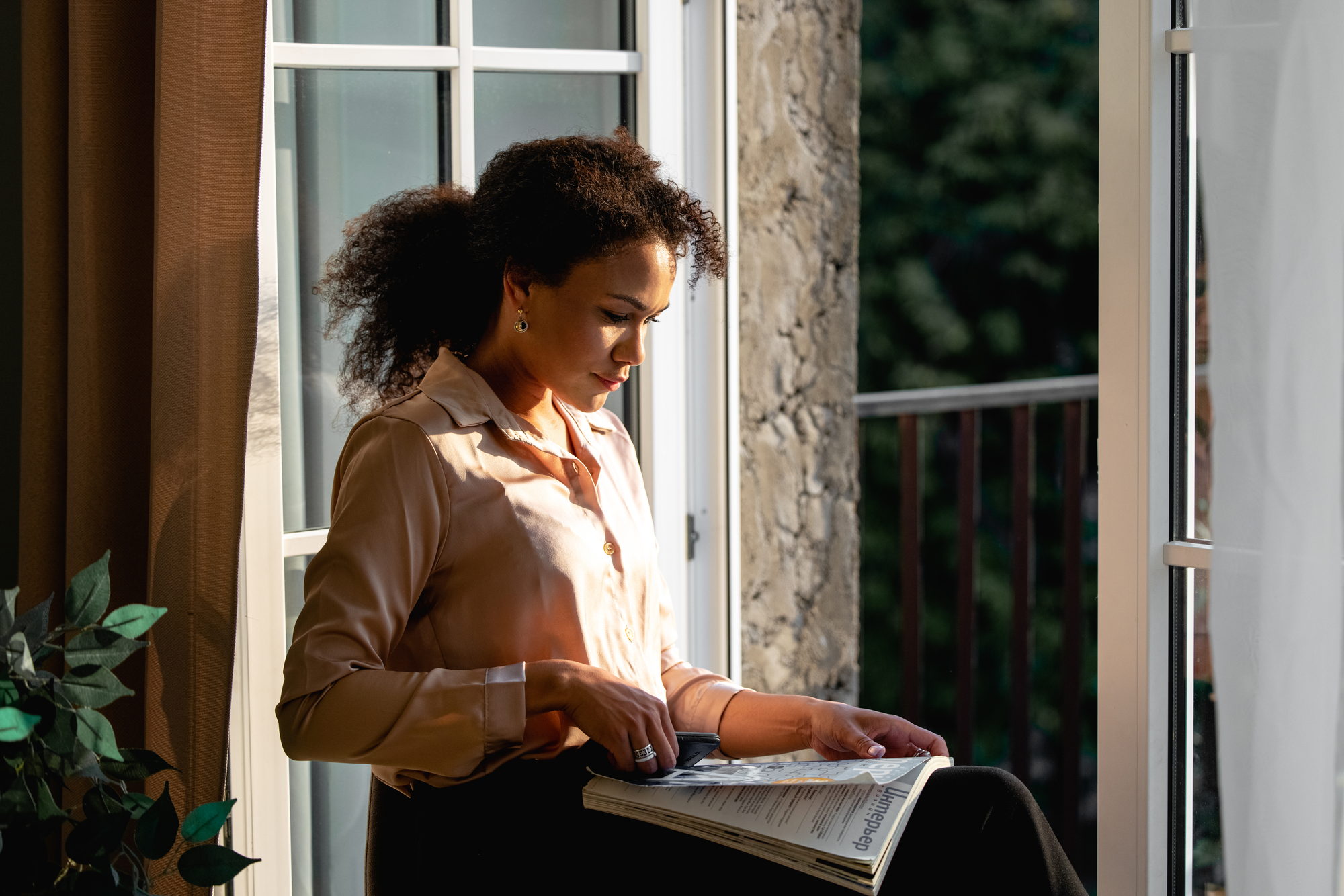A woman reading through documents by an open window