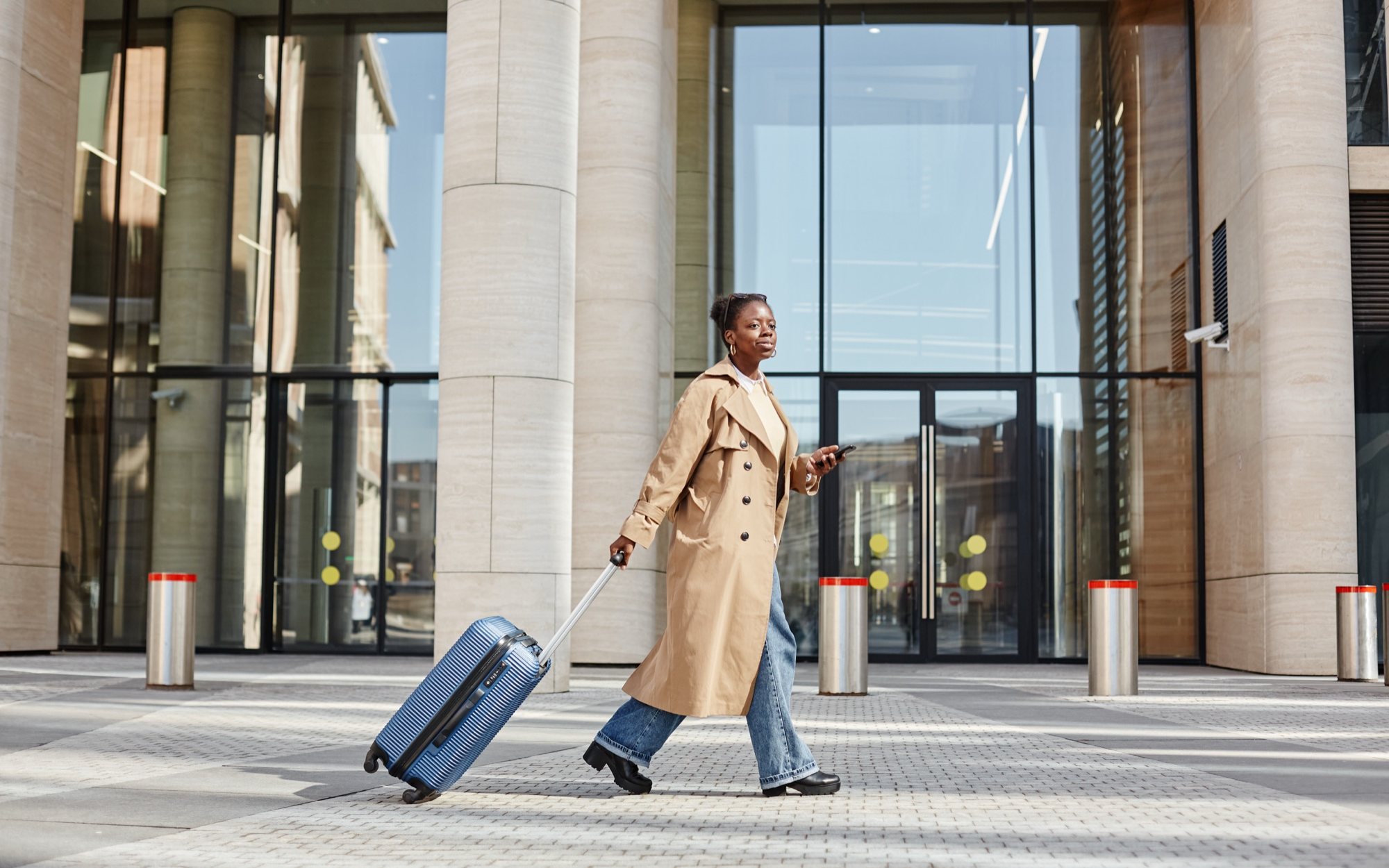 A traveller walking with a suitcase outside a modern station building