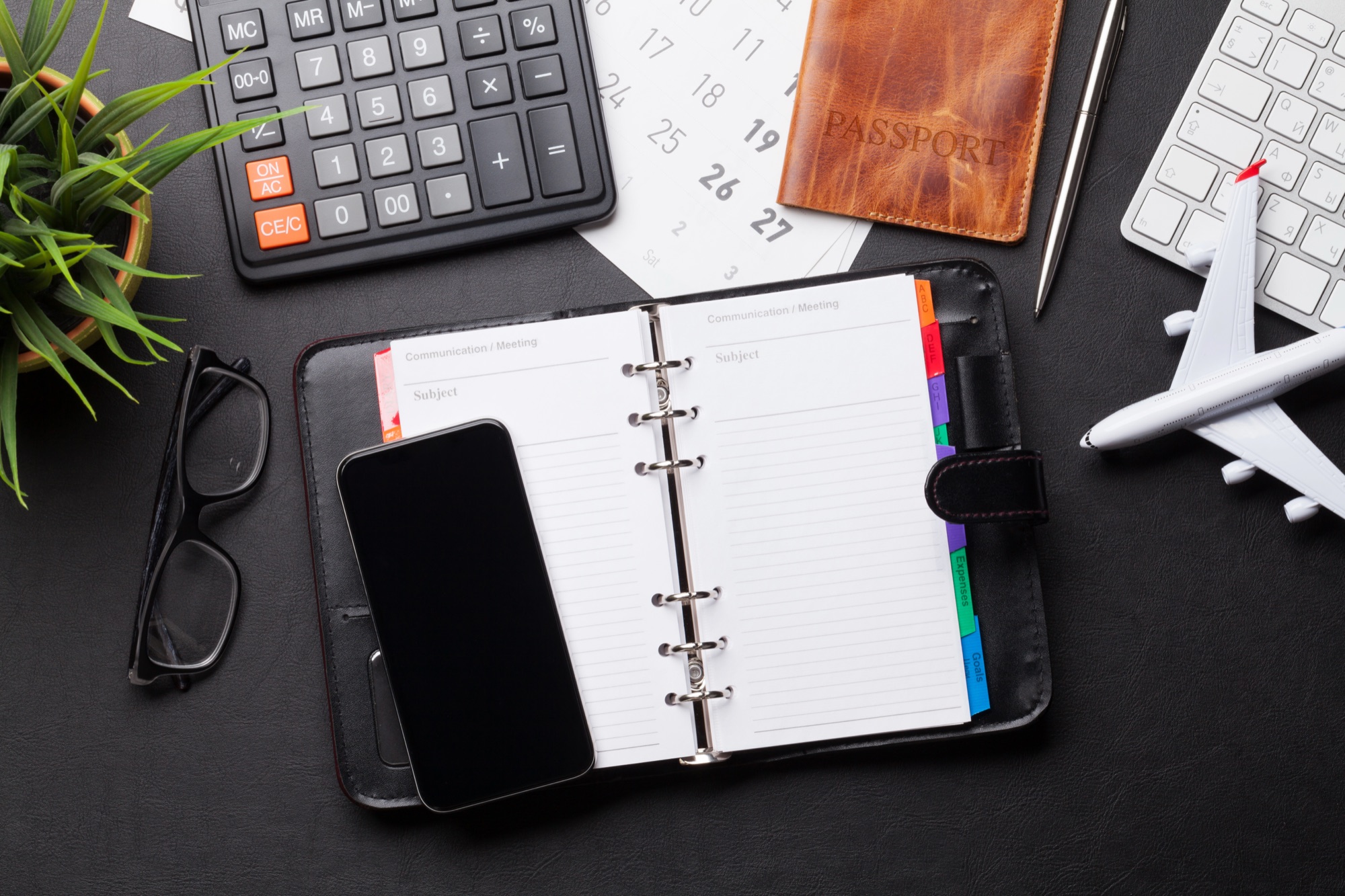 A travel planner, passport and phone on a desk