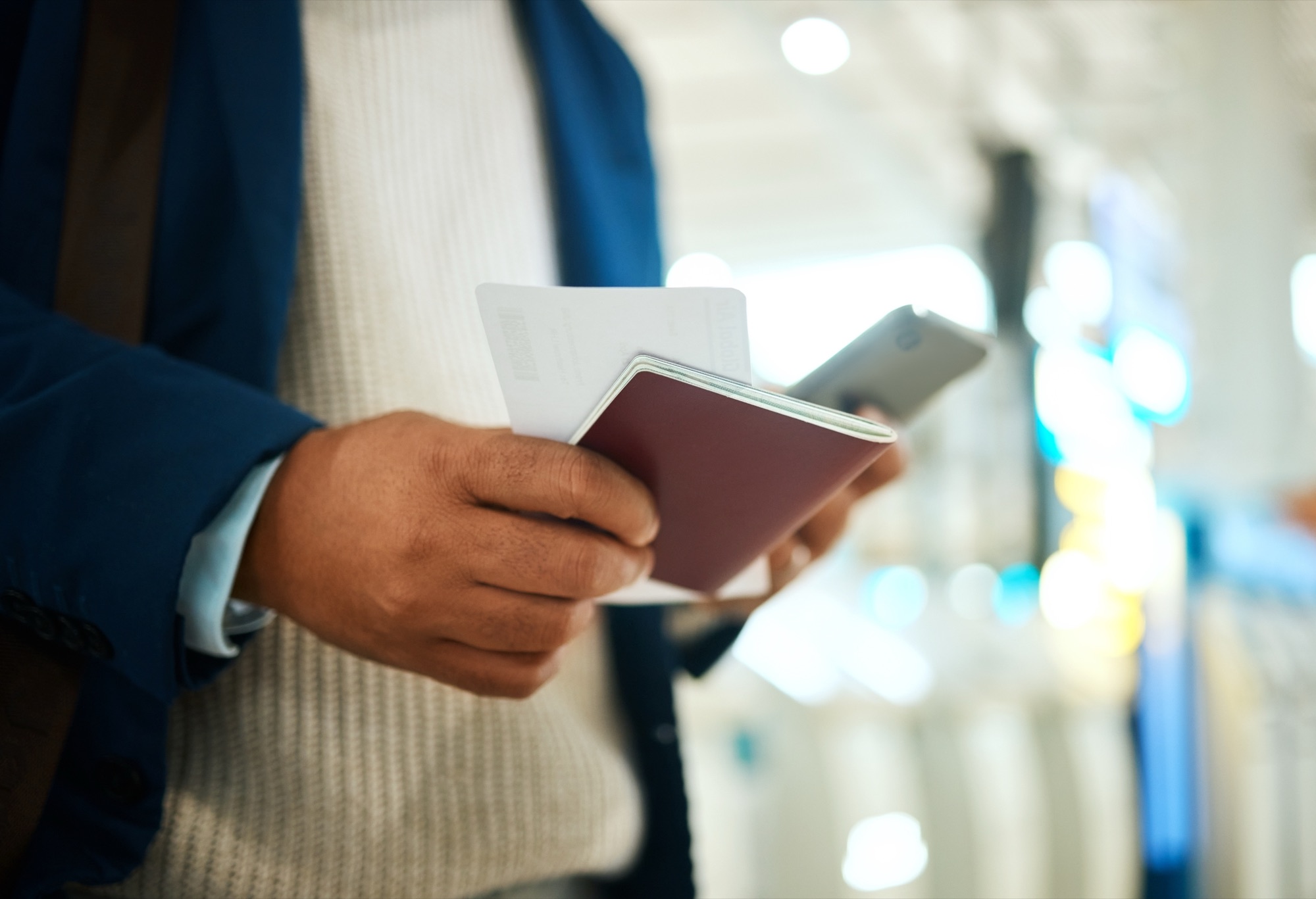 A traveller holding a passport, boarding pass and phone