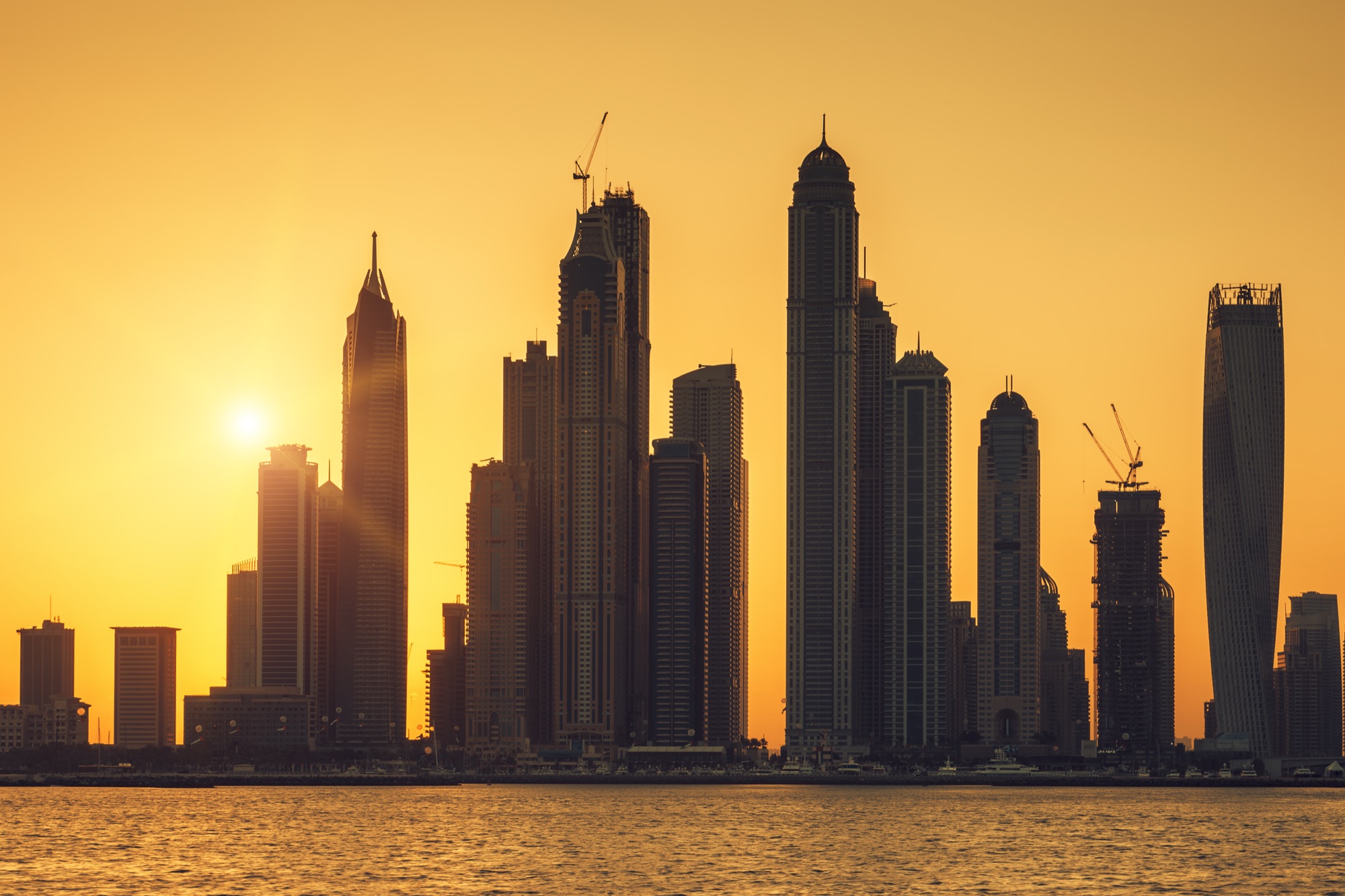 Dubai Marina towers in silhouette across the water at sunset