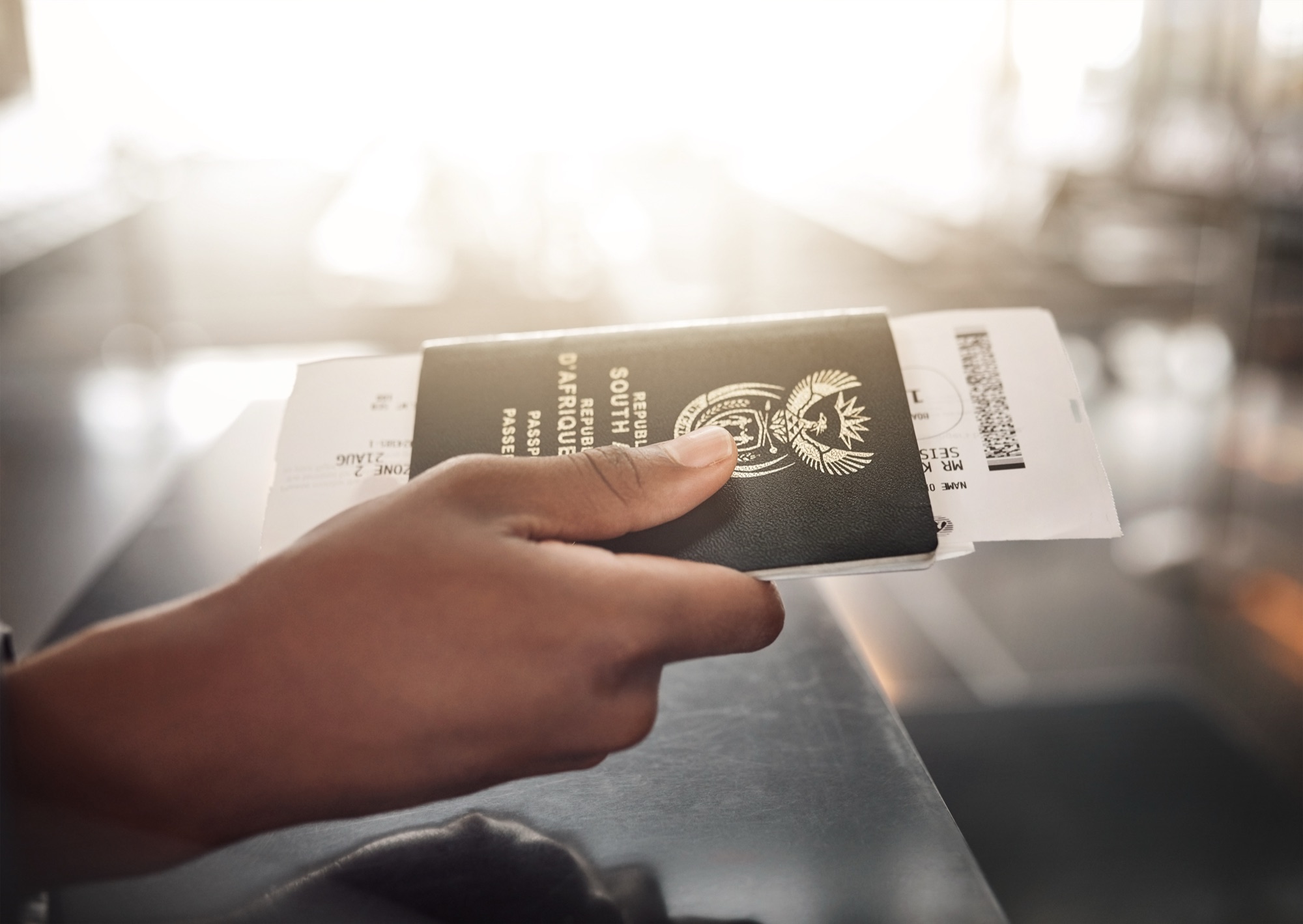 A South African passport and boarding pass held at an airport counter