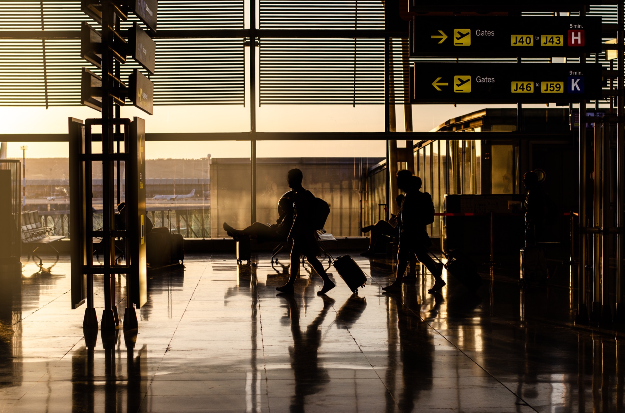 Travellers walking through an airport terminal at sunset