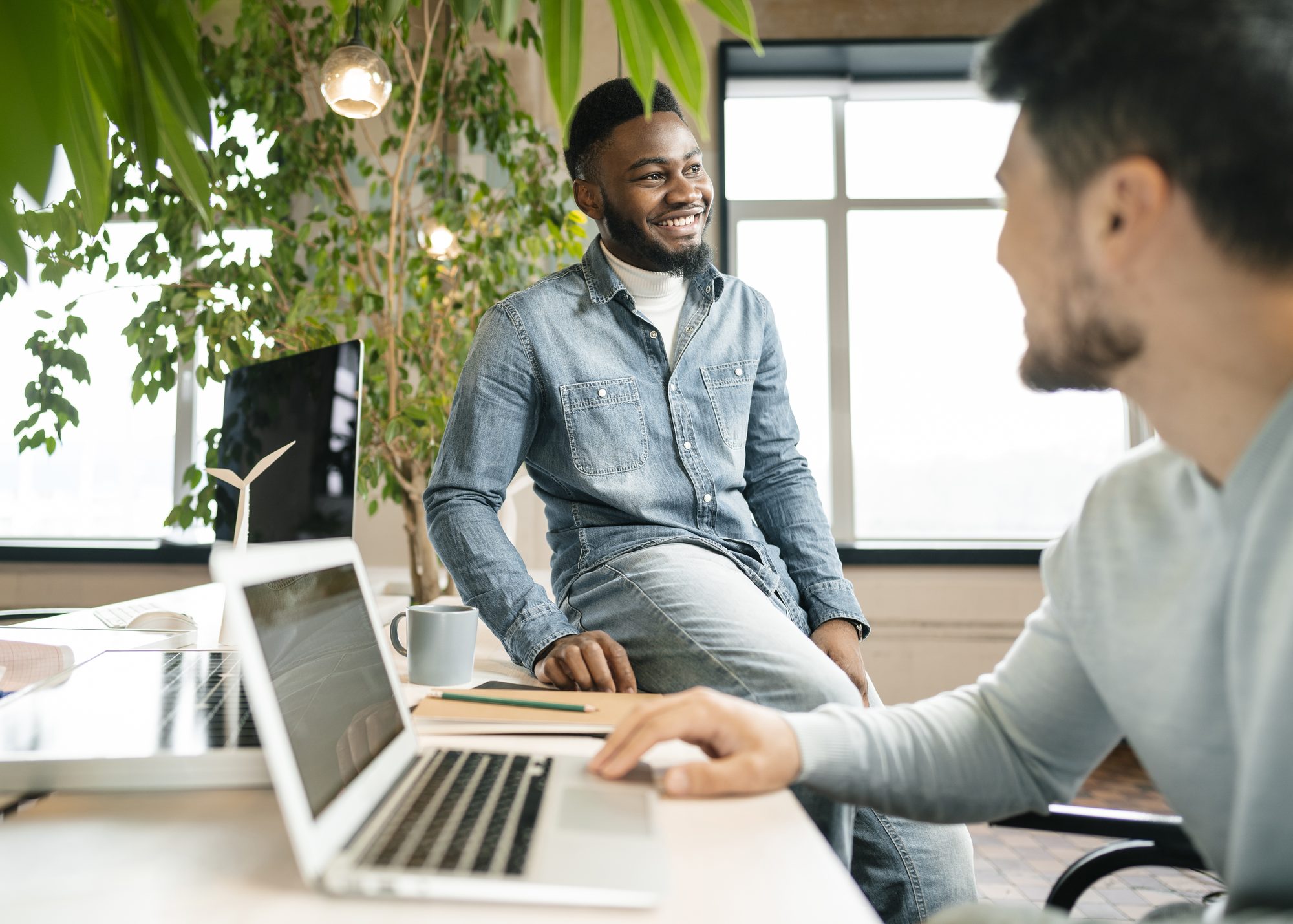Two professionals in a working conversation at a desk in a modern office