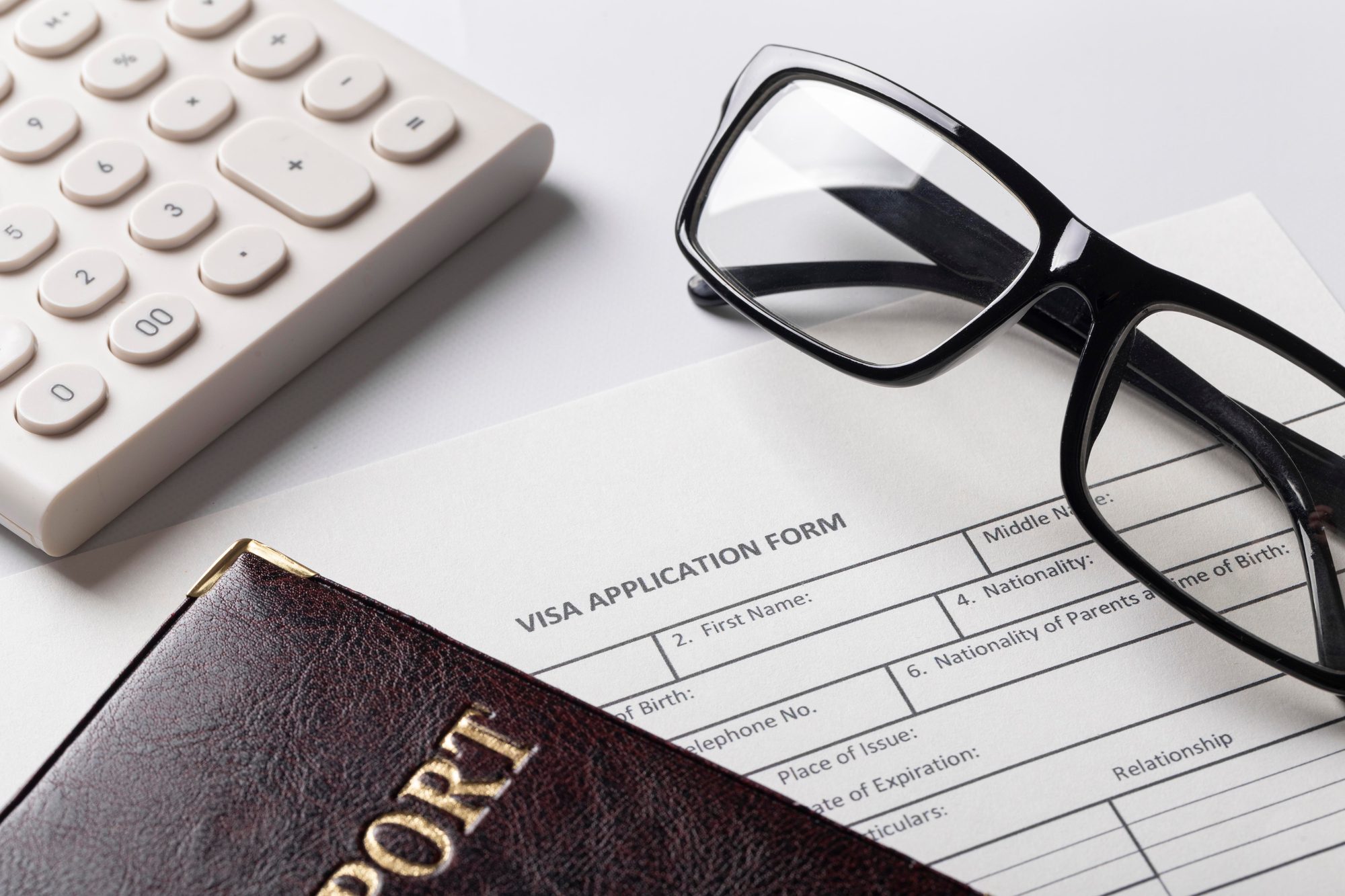 A passport resting on a printed visa application form on a desk