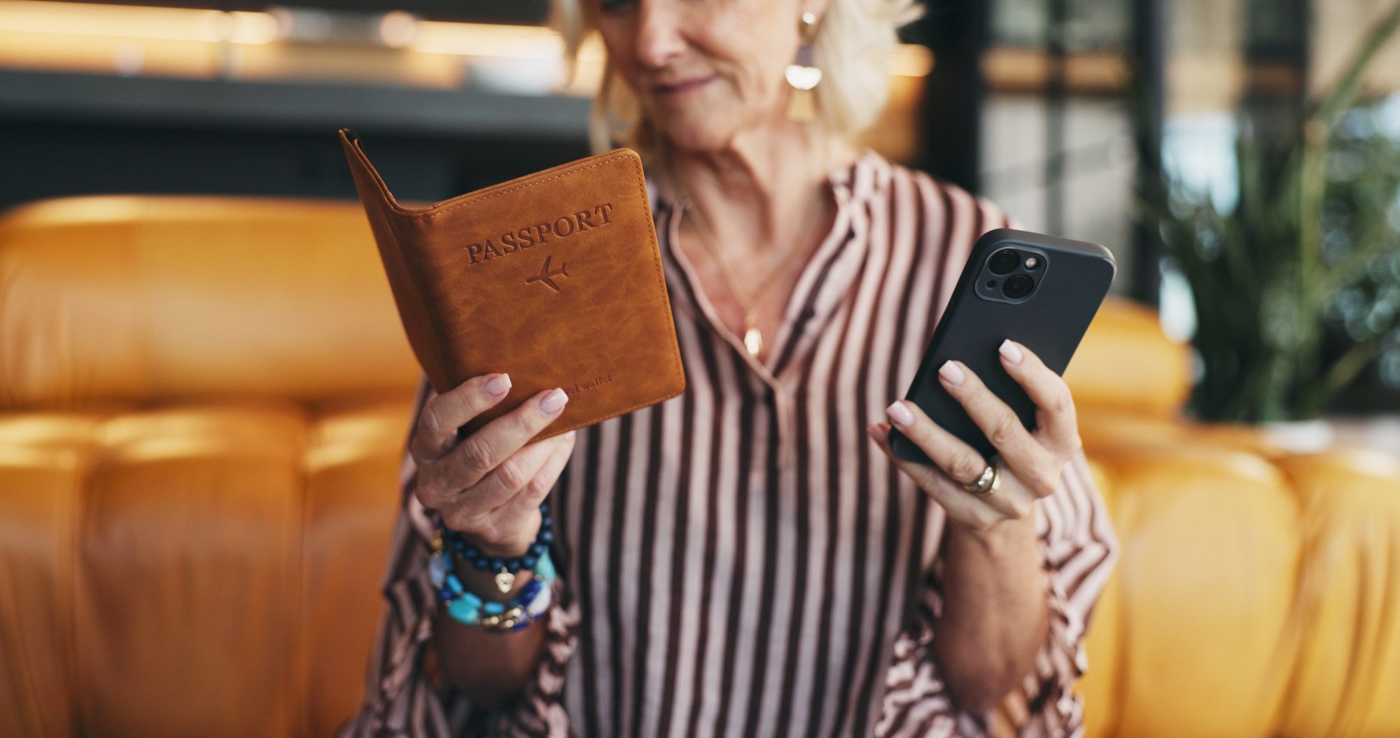 A traveller holding a passport holder in one hand and a phone in the other